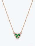 A rose gold box chain necklace featuring a heart-shaped pendant with a green heart in the center, surrounded by a halo of small clear stones and a tiny gold heart.